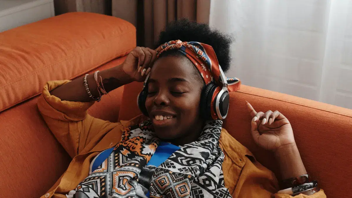a person in headphones relaxing on an orange sofa
