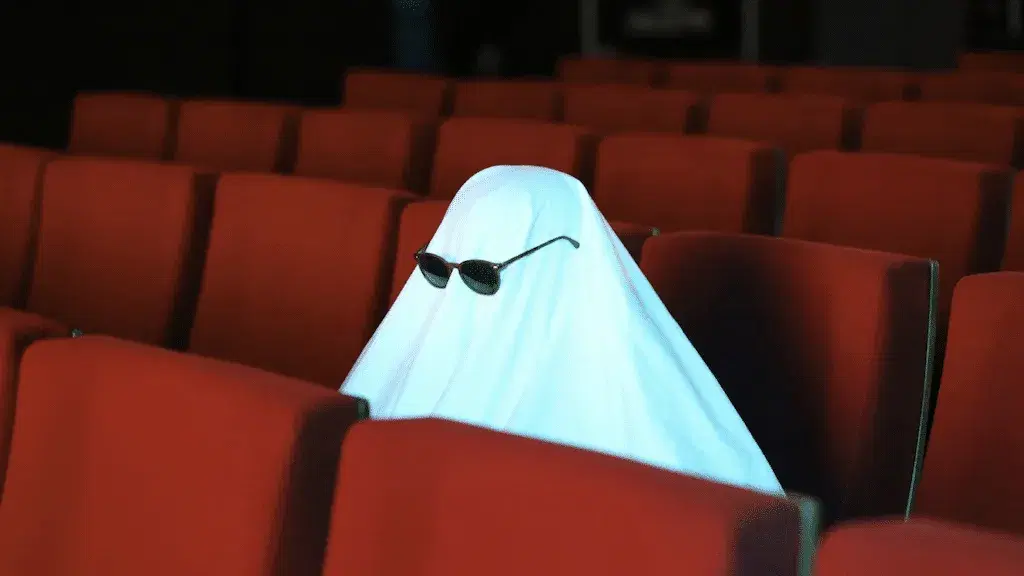 a ghost costume wearing sunglasses in a cinema seat