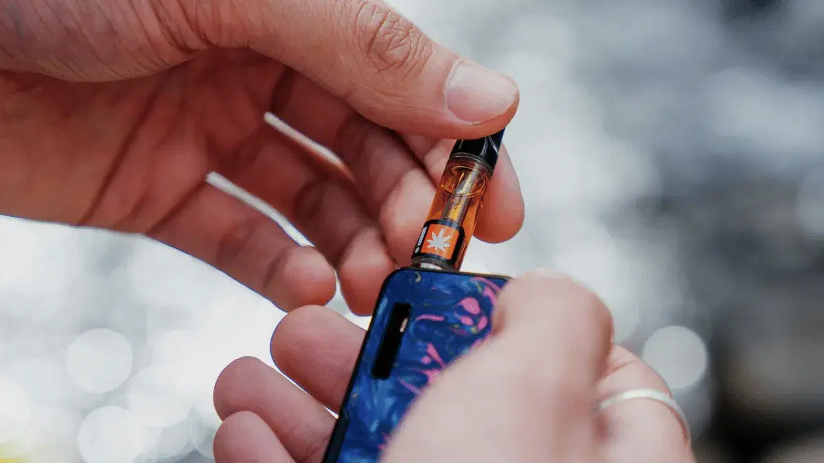 a hand holding a patterned vape battery and cartridge