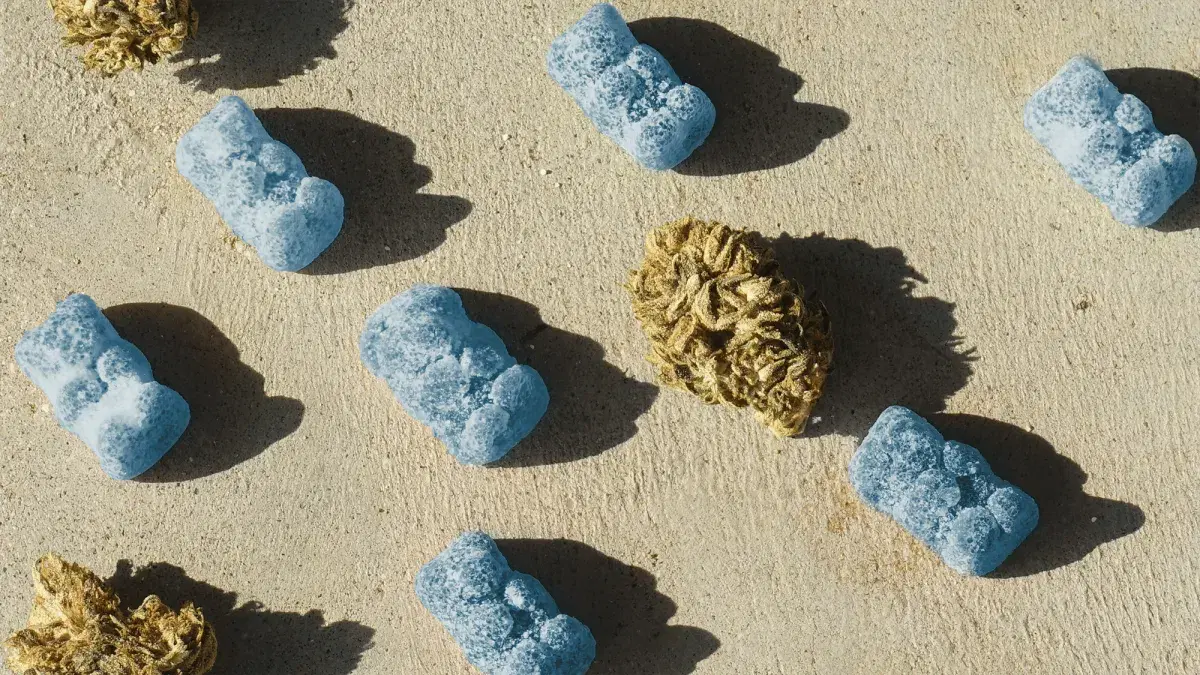 blue gummies and a cannabis bud on sand